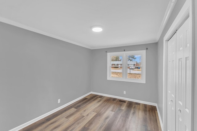 unfurnished bedroom featuring crown molding, hardwood / wood-style flooring, and a closet