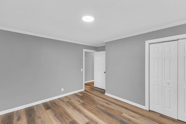 unfurnished bedroom featuring wood-type flooring, ornamental molding, and a closet