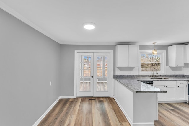 kitchen with stone countertops, decorative light fixtures, sink, and white cabinets