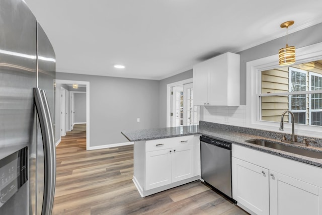 kitchen featuring appliances with stainless steel finishes, sink, white cabinets, hanging light fixtures, and kitchen peninsula