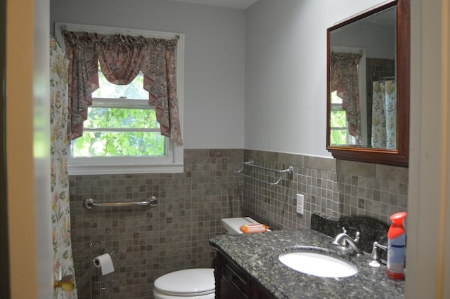 bathroom with vanity, toilet, and tile walls