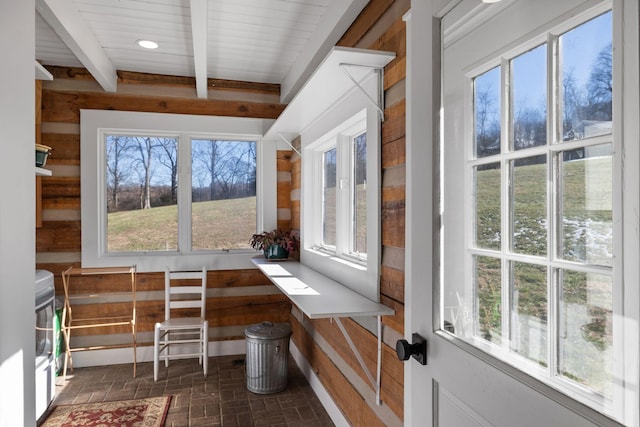 unfurnished sunroom featuring a healthy amount of sunlight and beamed ceiling