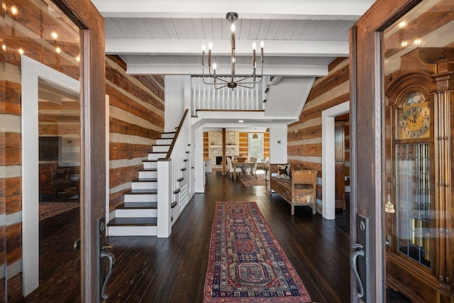 entrance foyer featuring an inviting chandelier, dark hardwood / wood-style flooring, beamed ceiling, and wood walls