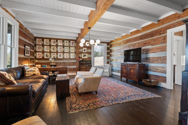 living room featuring beamed ceiling, dark hardwood / wood-style floors, a chandelier, and wood walls