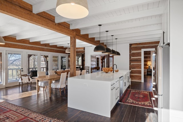 kitchen featuring sink, white cabinetry, hanging light fixtures, fridge, and a kitchen island with sink