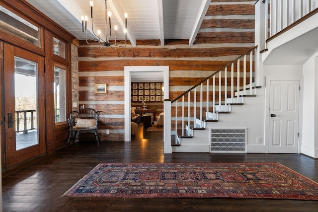 foyer entrance with dark wood-type flooring, wood walls, a chandelier, and beamed ceiling