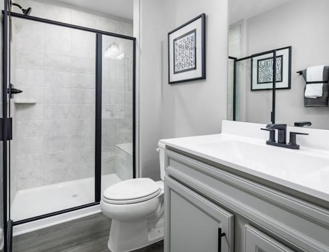 bathroom with vanity, hardwood / wood-style floors, an enclosed shower, and toilet