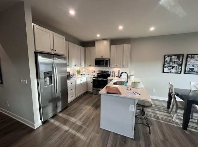 kitchen featuring sink, white cabinets, a kitchen breakfast bar, kitchen peninsula, and stainless steel appliances