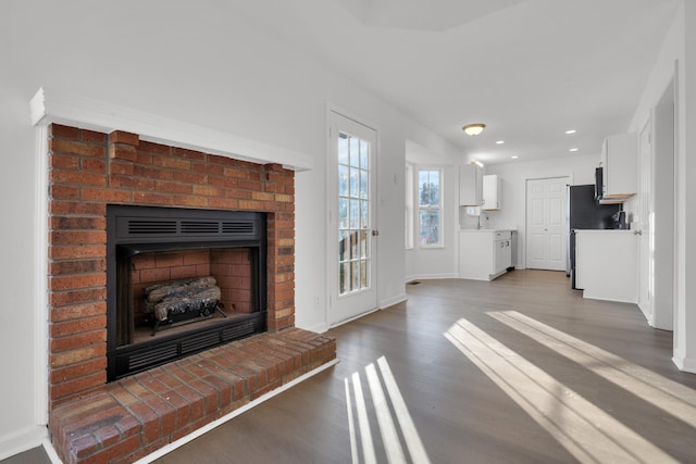 unfurnished living room featuring a fireplace, dark hardwood / wood-style floors, and sink