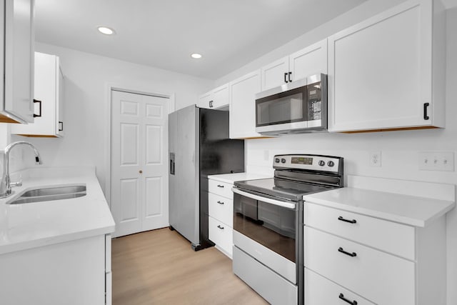 kitchen featuring stainless steel appliances, sink, white cabinets, and light hardwood / wood-style floors