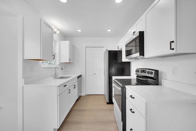 kitchen with white cabinetry, appliances with stainless steel finishes, sink, and light wood-type flooring