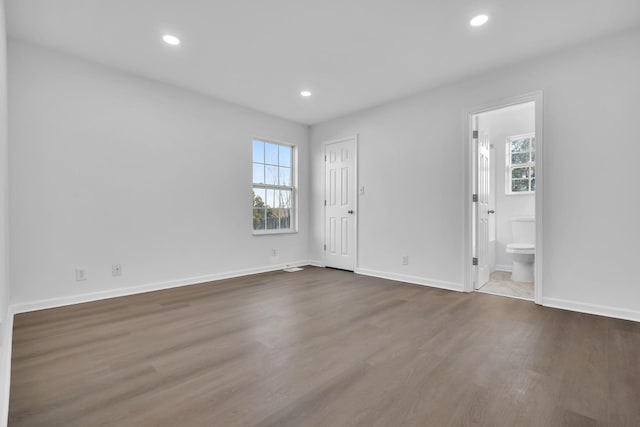 empty room with dark hardwood / wood-style flooring and plenty of natural light