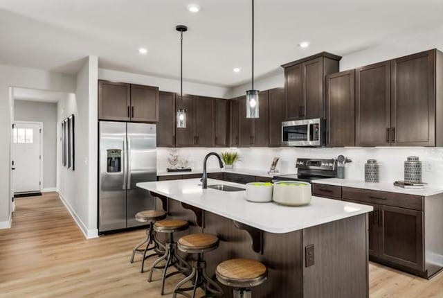 kitchen featuring pendant lighting, sink, a breakfast bar, stainless steel appliances, and a center island with sink