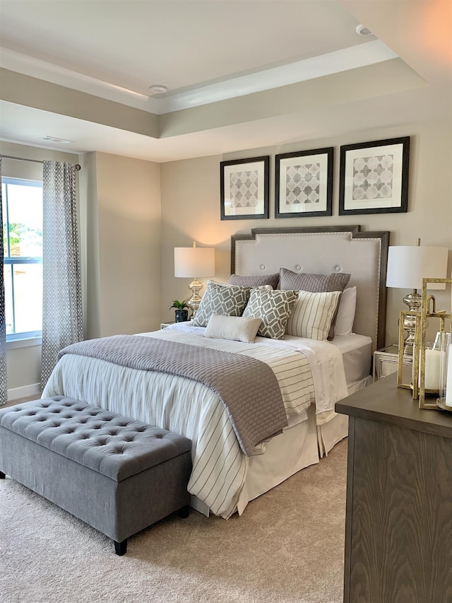 bedroom with a raised ceiling and light carpet