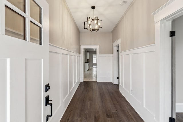 hall featuring an inviting chandelier, crown molding, and dark hardwood / wood-style floors