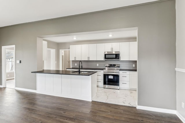 kitchen with white cabinetry, sink, decorative backsplash, kitchen peninsula, and stainless steel appliances