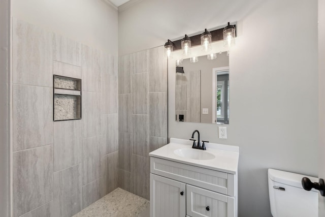 bathroom featuring vanity, a tile shower, and toilet