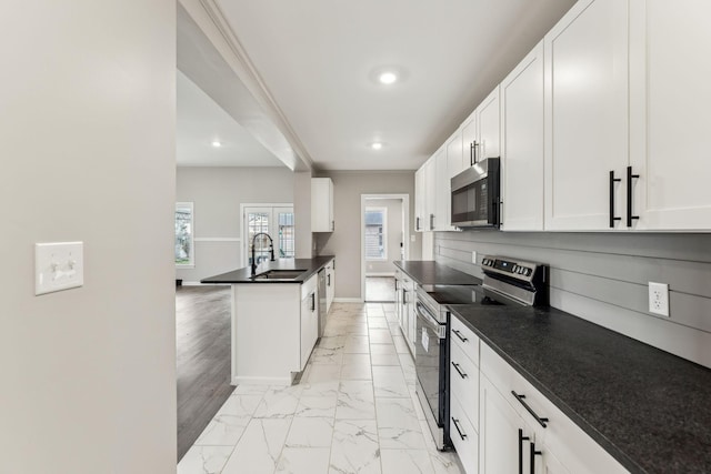 kitchen with white cabinetry, appliances with stainless steel finishes, sink, and an island with sink