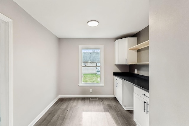 kitchen with white cabinetry, dark wood-type flooring, and built in desk