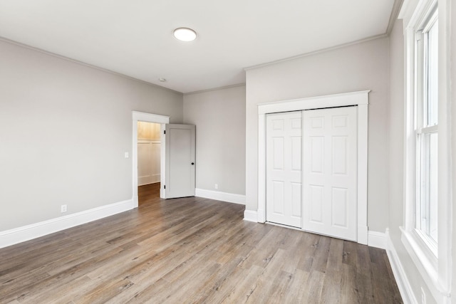 unfurnished bedroom with ornamental molding, light wood-type flooring, and a closet