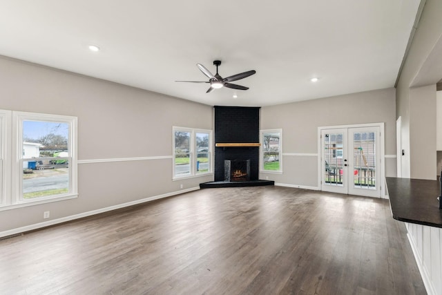 unfurnished living room featuring french doors, ceiling fan, wood-type flooring, and a fireplace