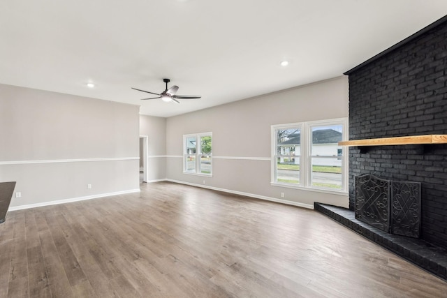 unfurnished living room featuring a brick fireplace, hardwood / wood-style floors, and ceiling fan