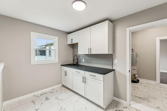 kitchen with white cabinetry, sink, and gas water heater