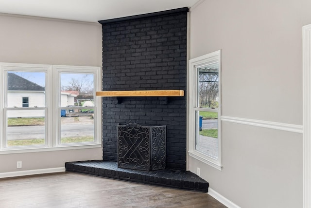 unfurnished living room with hardwood / wood-style flooring, ornamental molding, a healthy amount of sunlight, and a fireplace