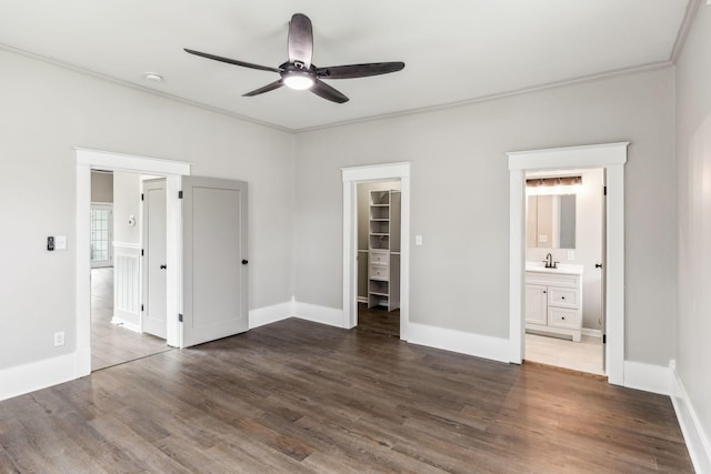 unfurnished bedroom with connected bathroom, sink, a walk in closet, ornamental molding, and dark hardwood / wood-style flooring