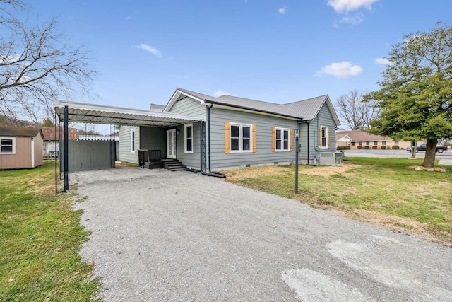 view of front of home featuring a carport, central AC, a front lawn, and a storage shed