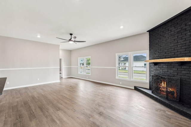 unfurnished living room with hardwood / wood-style flooring, ceiling fan, and a fireplace