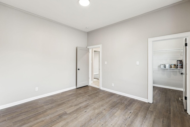 unfurnished bedroom with a closet, dark wood-type flooring, and a spacious closet