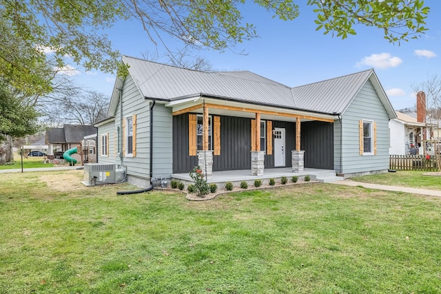 view of front of home with central AC unit, a front yard, and covered porch