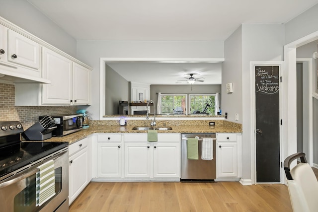 kitchen with stainless steel appliances, white cabinetry, sink, and stone countertops