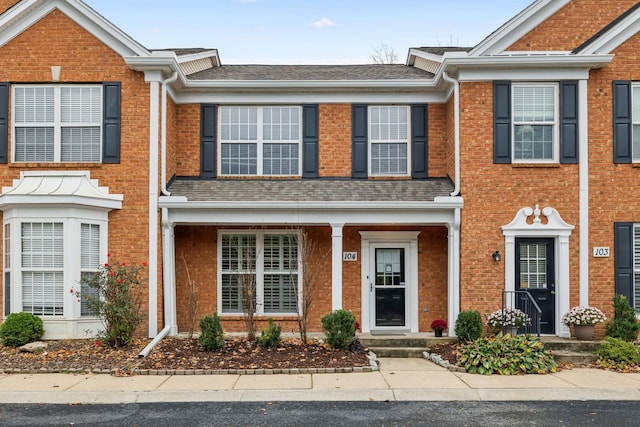 townhome / multi-family property with brick siding and a shingled roof