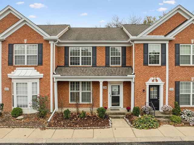 townhome / multi-family property featuring brick siding and roof with shingles