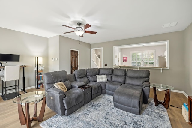 living room with ceiling fan, sink, and light wood-type flooring