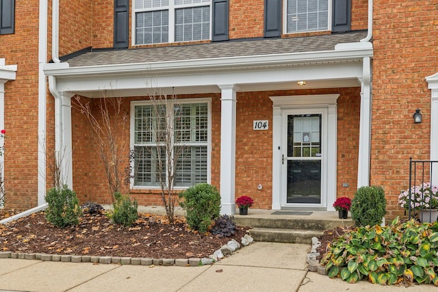 property entrance with brick siding and a shingled roof