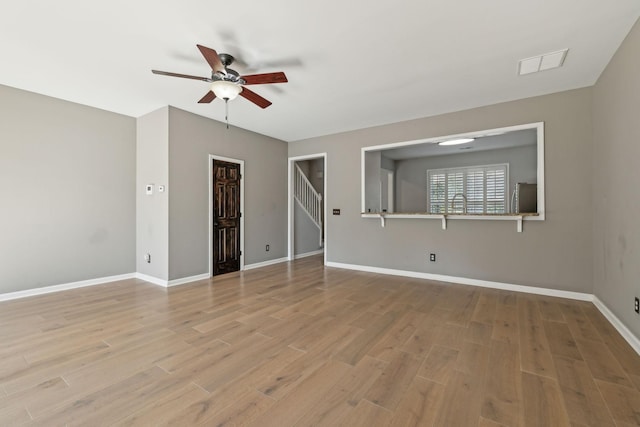 spare room featuring visible vents, a ceiling fan, baseboards, and wood finished floors