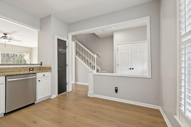 kitchen with dishwasher, light stone counters, baseboards, and light wood finished floors