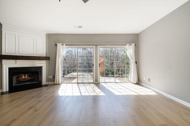 unfurnished living room featuring visible vents, plenty of natural light, and wood finished floors