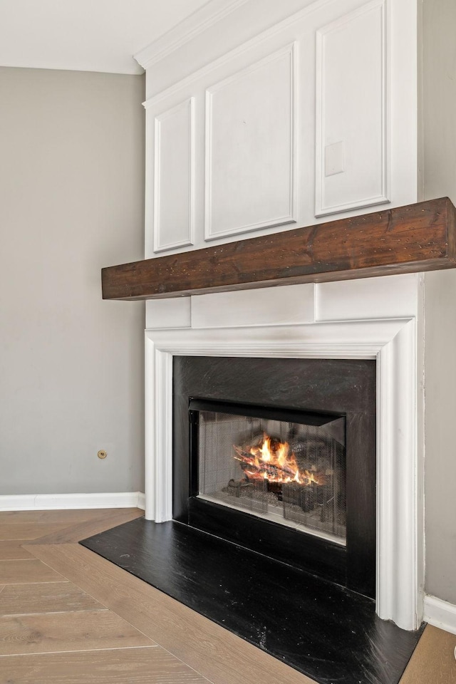 interior details with baseboards and a lit fireplace