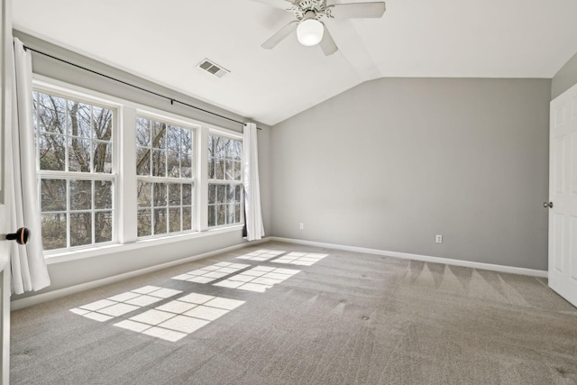 spare room with a wealth of natural light, visible vents, lofted ceiling, and carpet