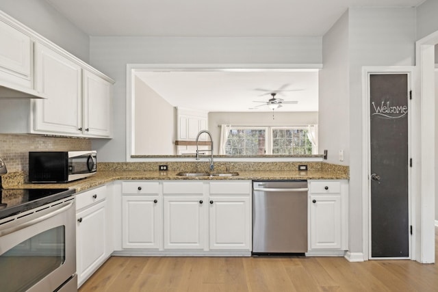 kitchen with light stone counters, decorative backsplash, appliances with stainless steel finishes, and light wood-style flooring