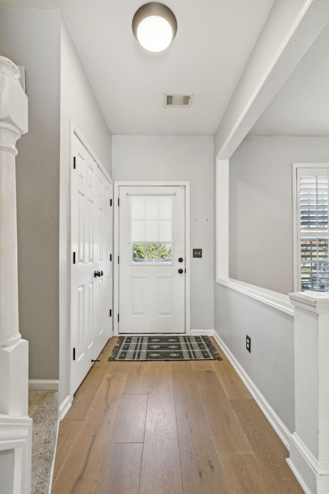 doorway to outside with visible vents, decorative columns, baseboards, and hardwood / wood-style flooring