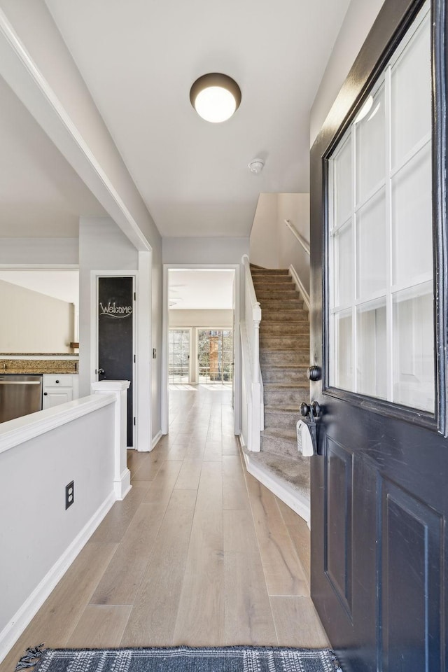 foyer entrance with stairs, wood finished floors, and baseboards