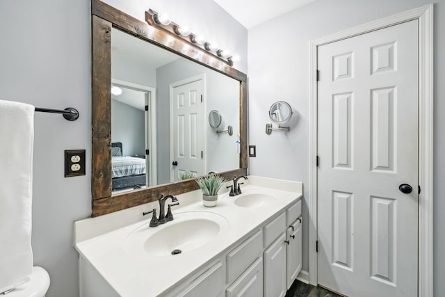 bathroom with double vanity, connected bathroom, toilet, and a sink