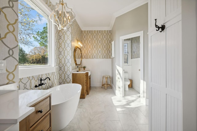 bathroom featuring a chandelier, ornamental molding, vanity, a washtub, and toilet