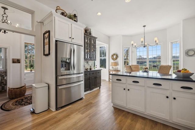 kitchen featuring hanging light fixtures, stainless steel fridge, white cabinets, and light wood-type flooring