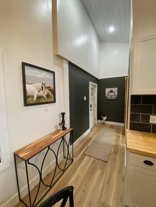 doorway with wooden walls and light hardwood / wood-style flooring